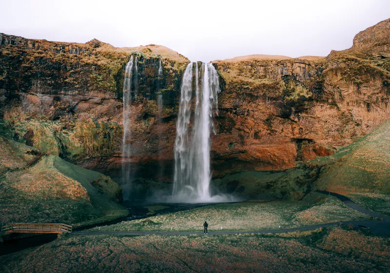 A person in front of Seljalandsfoss waterfall, drone photo in autumn
