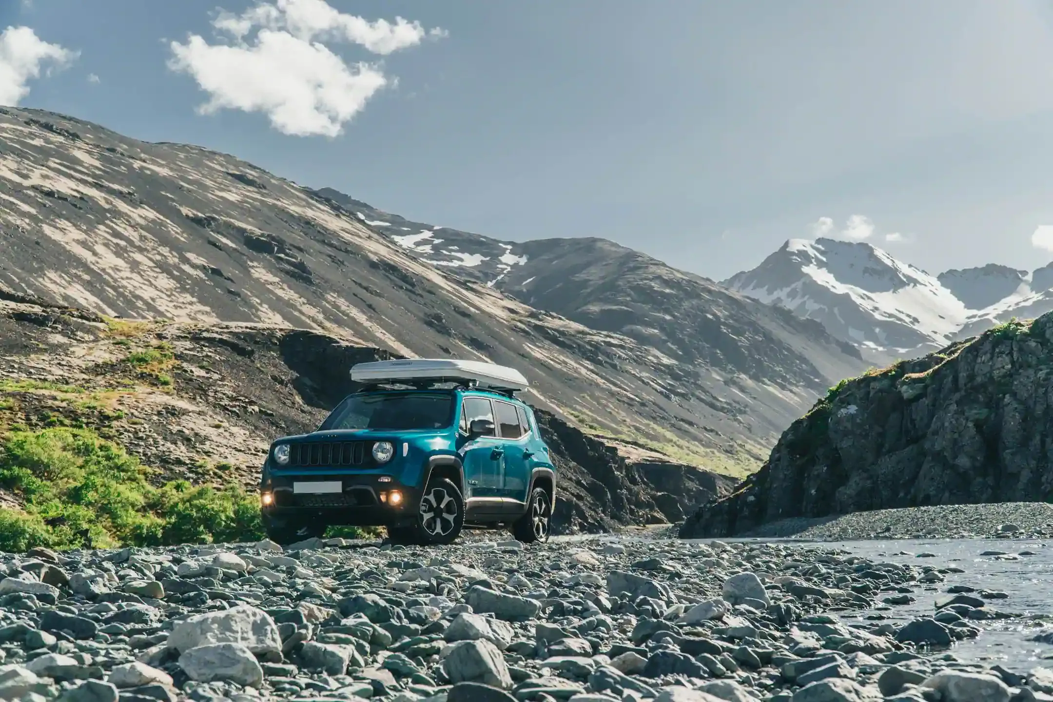 Jeep Renegade 4xe driving through a rocky riverbed on a Highland route in Iceland