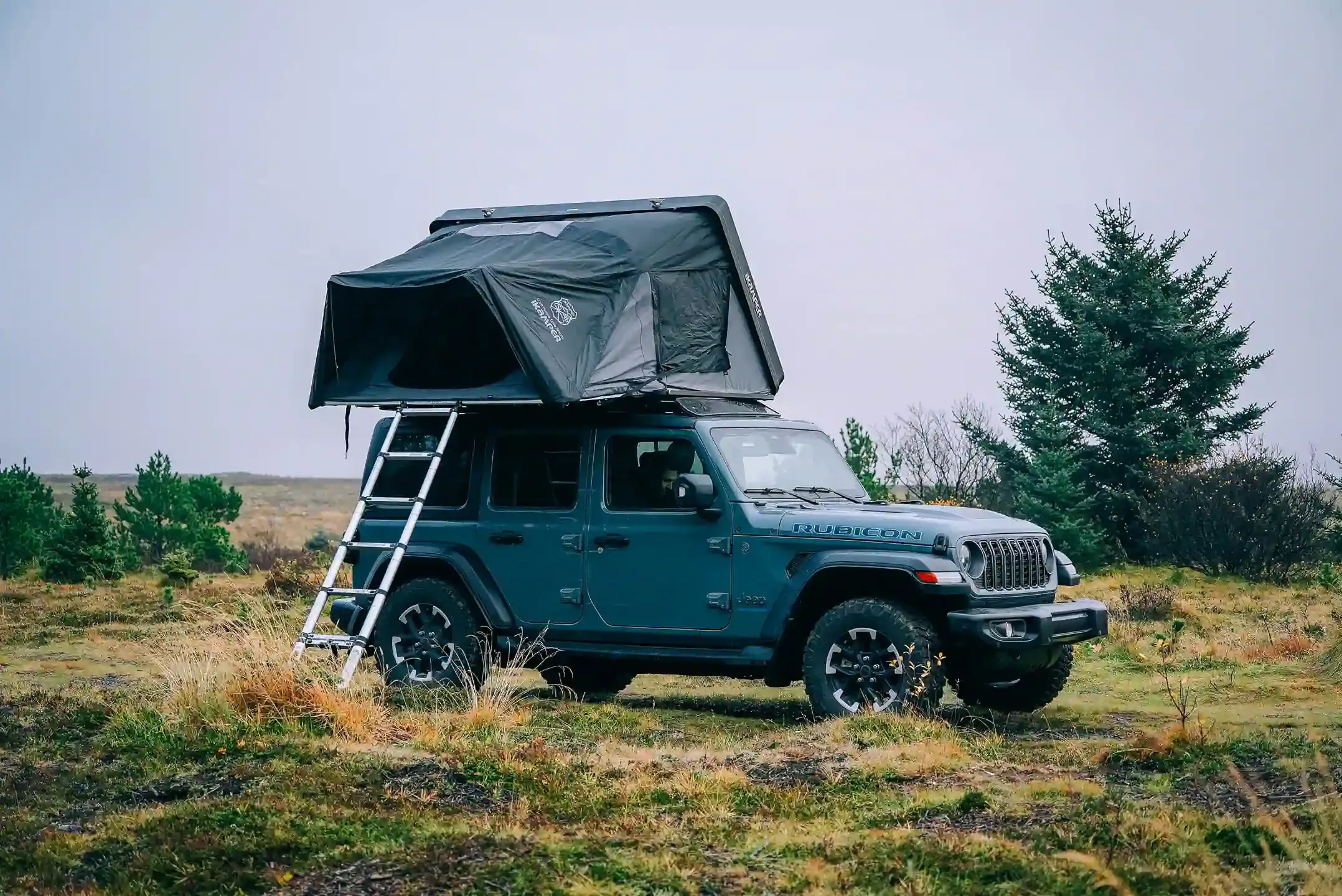 Jeep Wrangler 4x4 with rooftop tent and access ladder parked on grass ready for Icelandic camping adventure