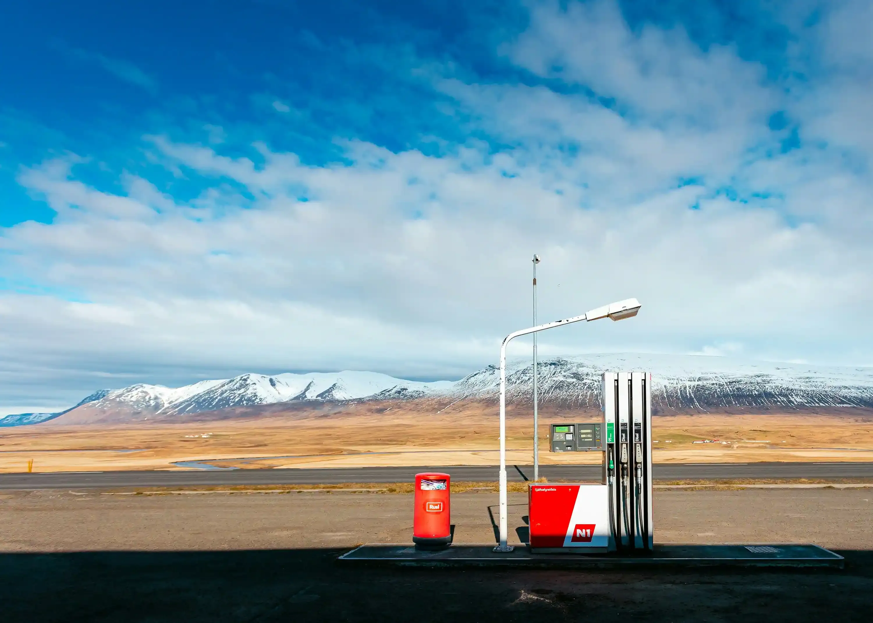 N1 gas station in Iceland with fuel pumps in front of snow-covered mountains during a campervan road trip 