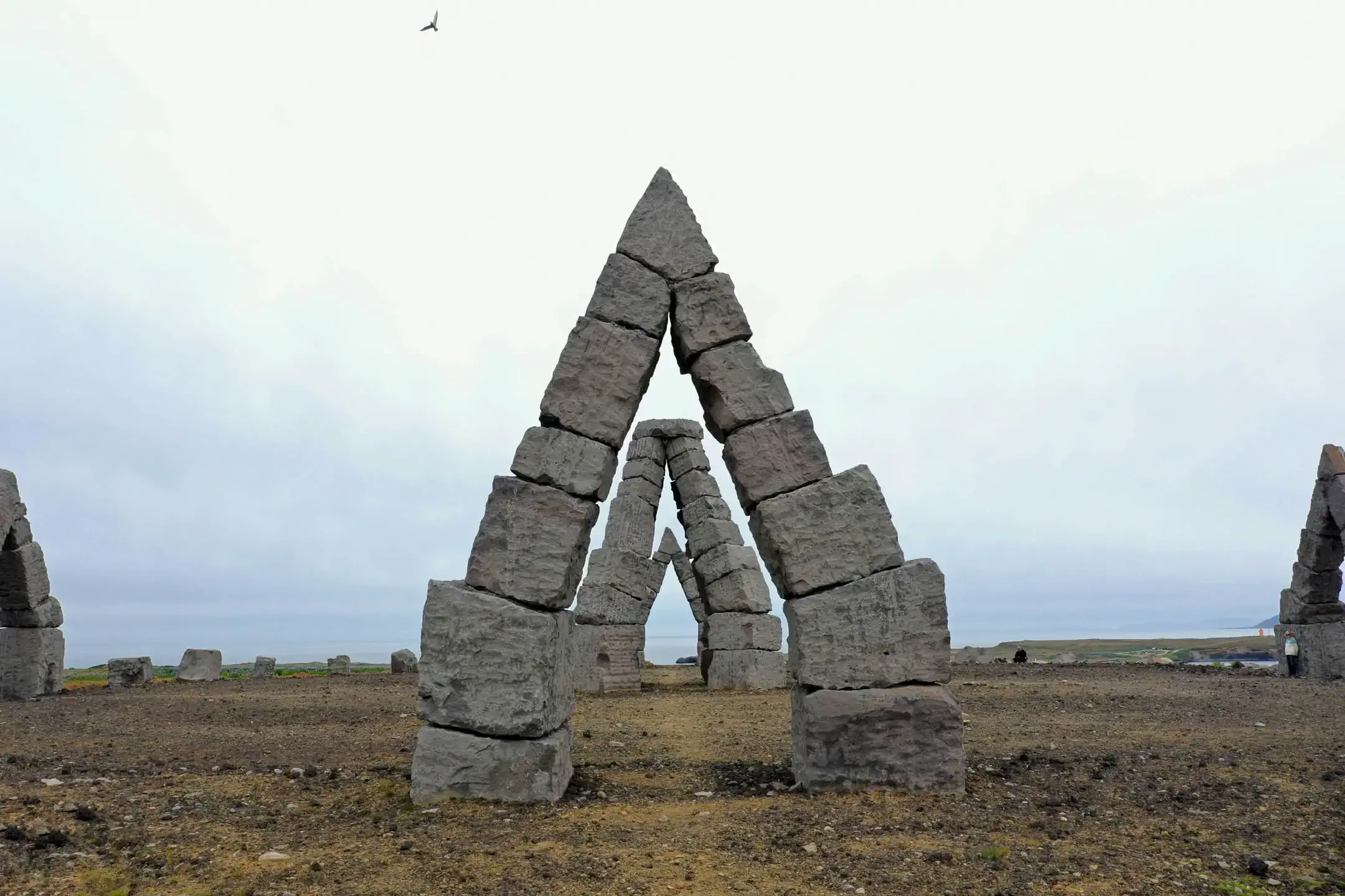 El Arctic Henge en un día nublado: bloques triangulares de basalto forman puertas geométricas sobre un paisaje volcánico desnudo del norte de Islandia
