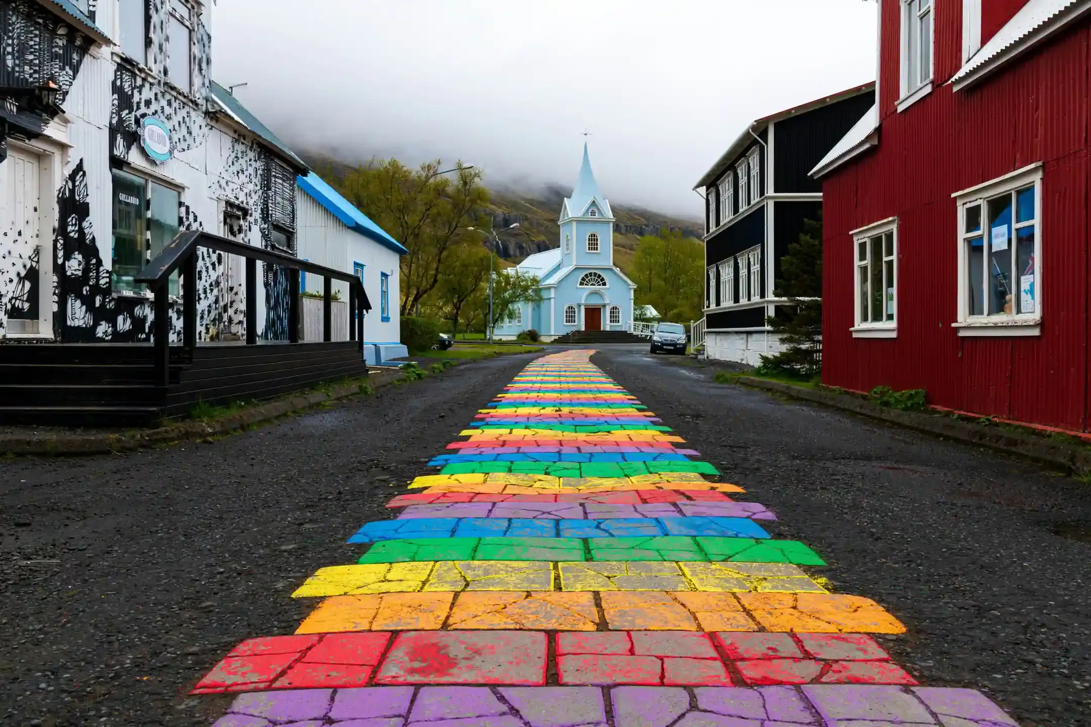Colorful Rainbow Street leading to the blue church in Seyðisfjörður village in East Iceland