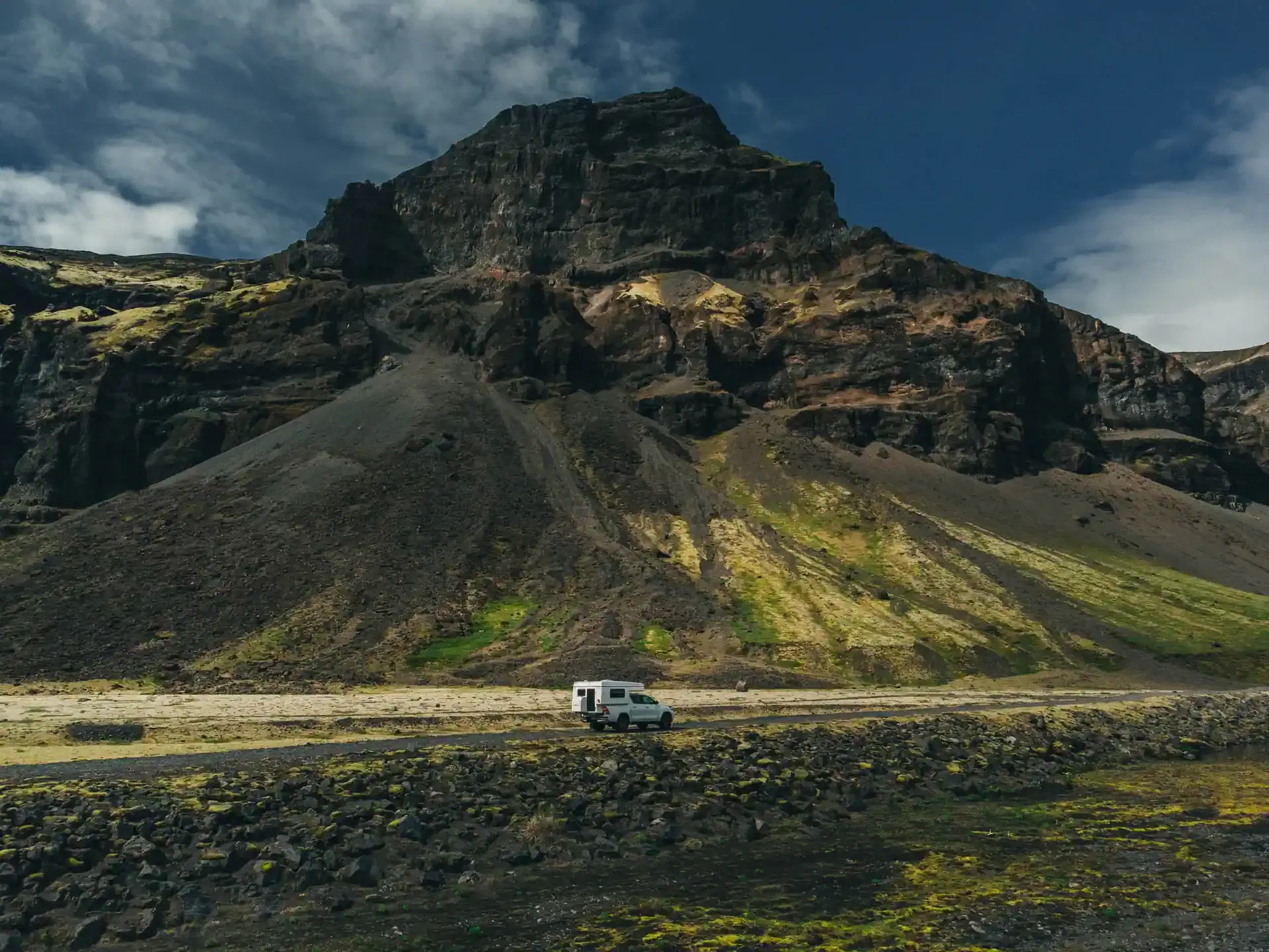 Campervan parked below a steep volcanic mountain in Iceland’s highlands.