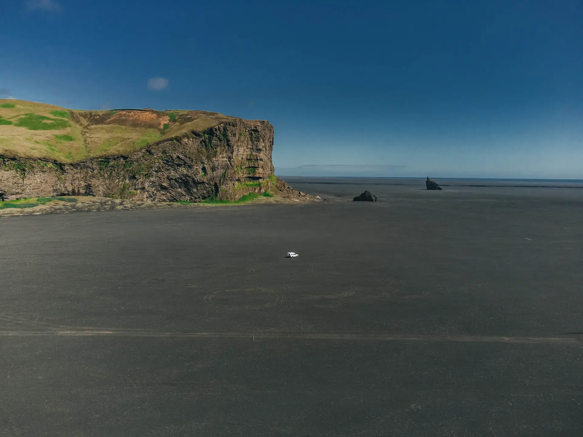 Campervan parked alone on a vast black sand desert in South Iceland, illustrating iceland crowd free campervan routes.