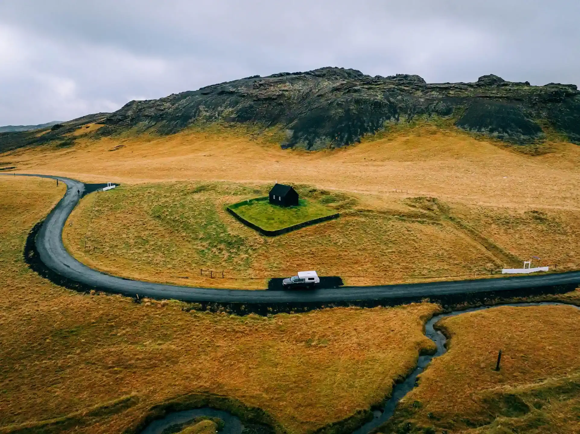 Golden Circle Snaefellsnes campervan itinerary with a 4x4 camper driving past a historic black church in Iceland
