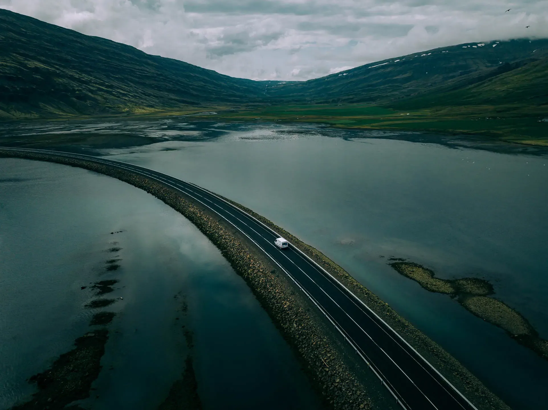 Campervan driving along the Ring Road in Iceland through a fjord landscape during an Iceland campervan road trip