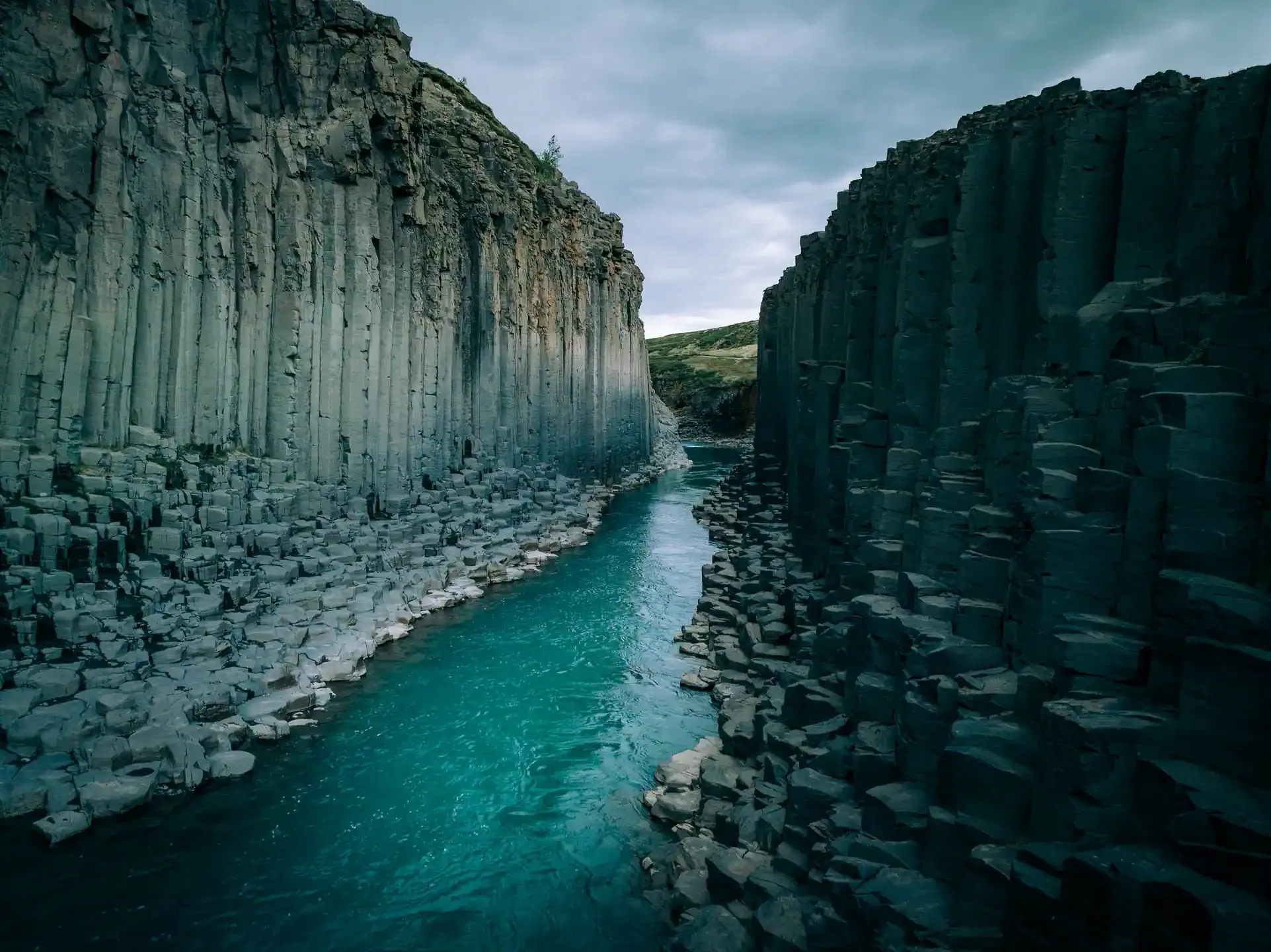 Studlagil Canyon in East Iceland with turquoise river flowing between basalt column cliffs

