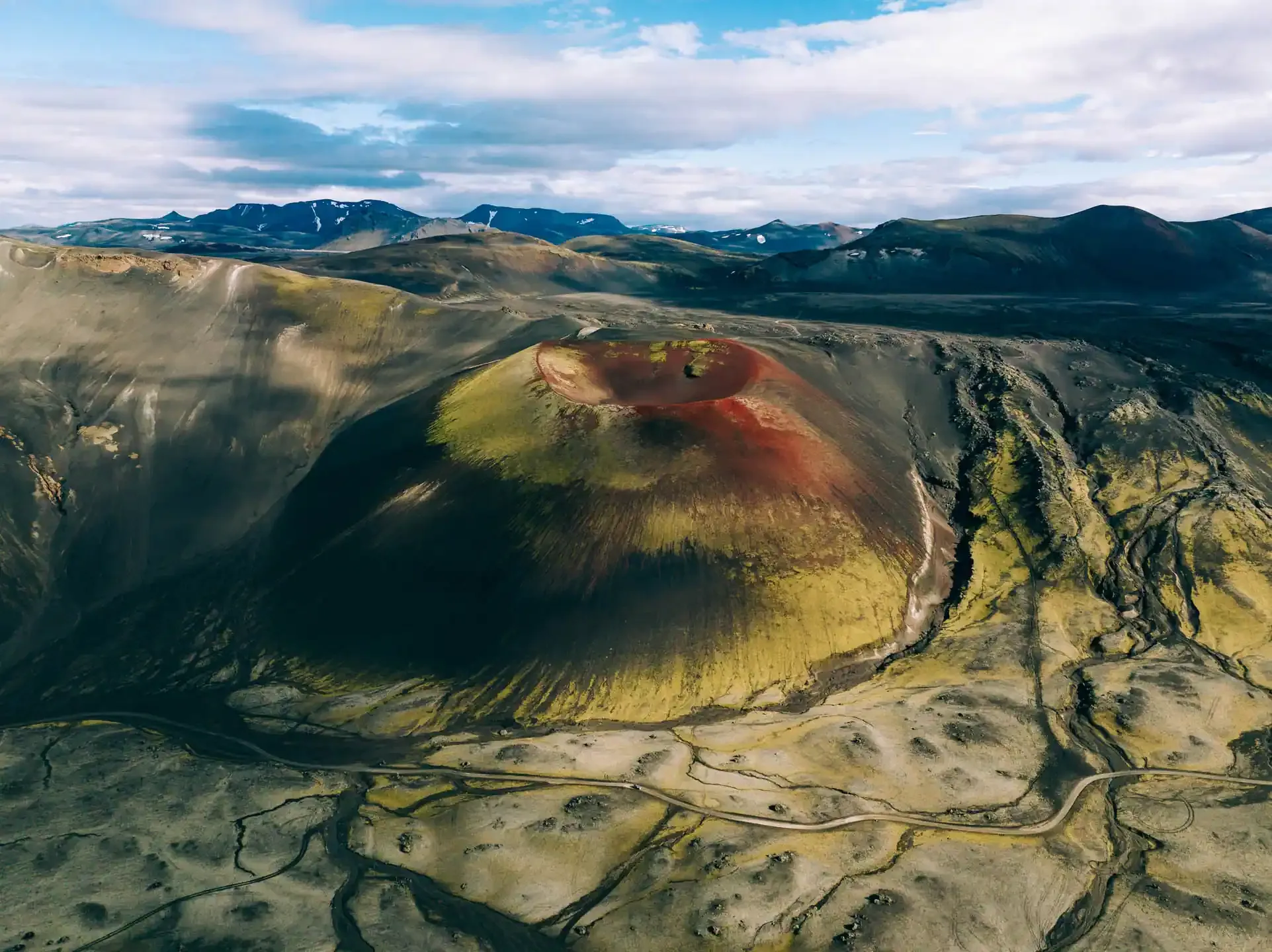 Colorful volcanic crater with red, green, and black landscape patterns
