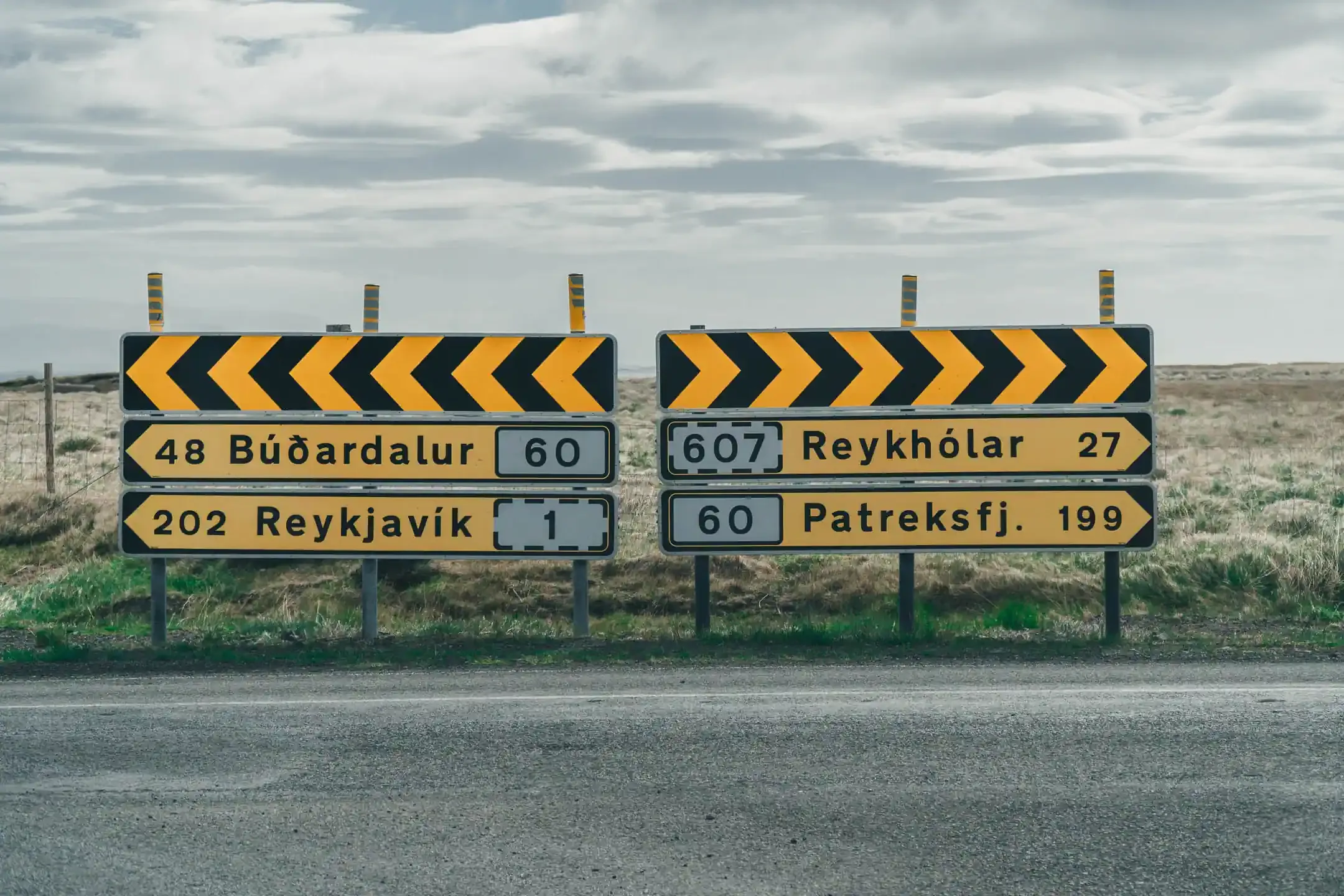 Directional road signs in rural Iceland showing distances to Reykjavík, Reykhólar, Búðardalur, and Patreksfjörður during a campervan road trip