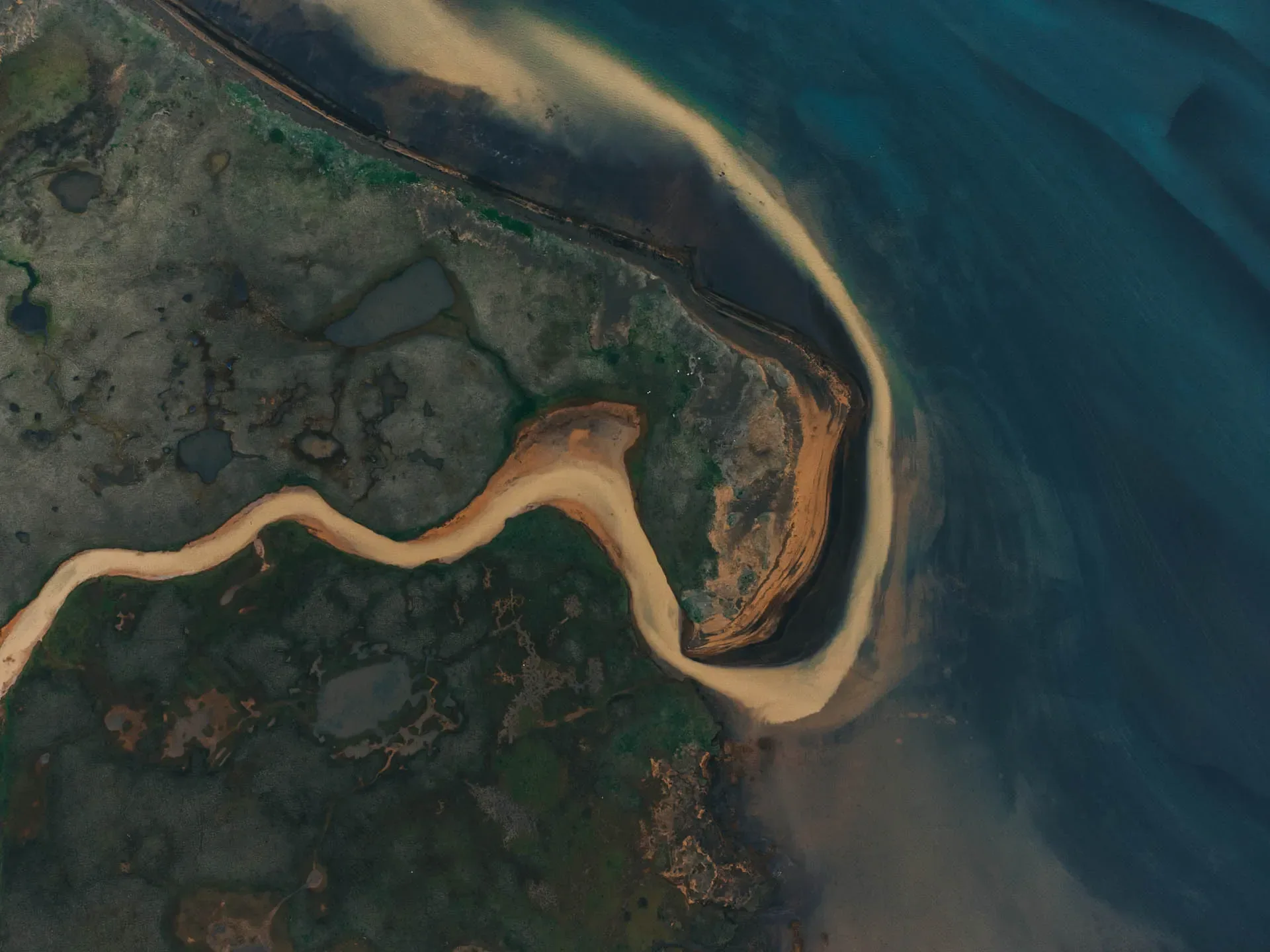 Aerial view of a river flowing into the ocean along Iceland’s rugged coastline 