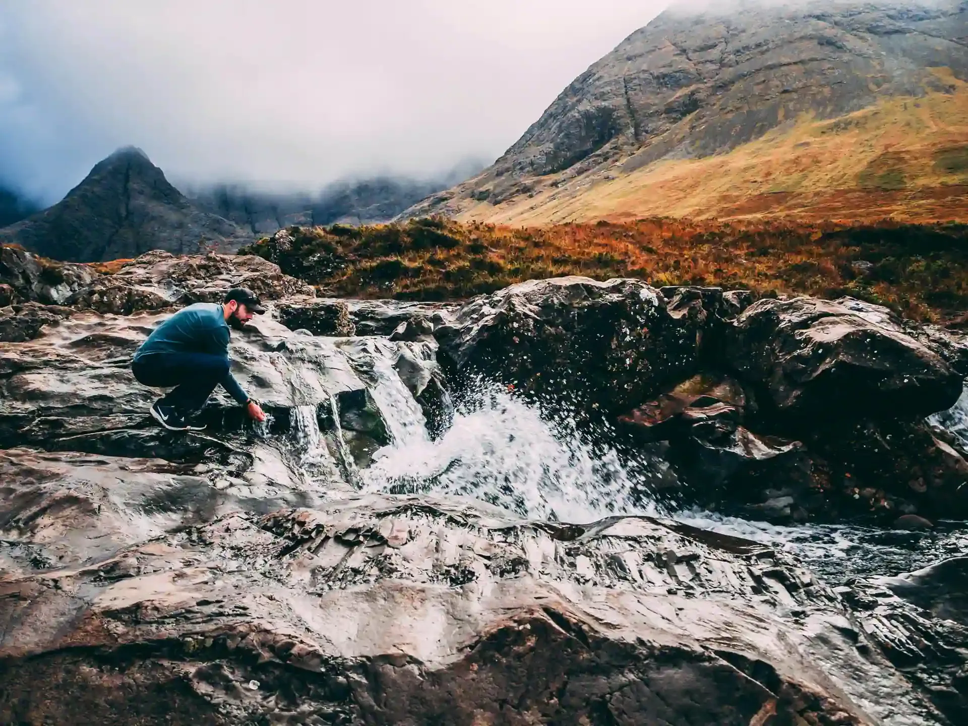 Traveler filling a bottle from a clear fast moving stream in Iceland