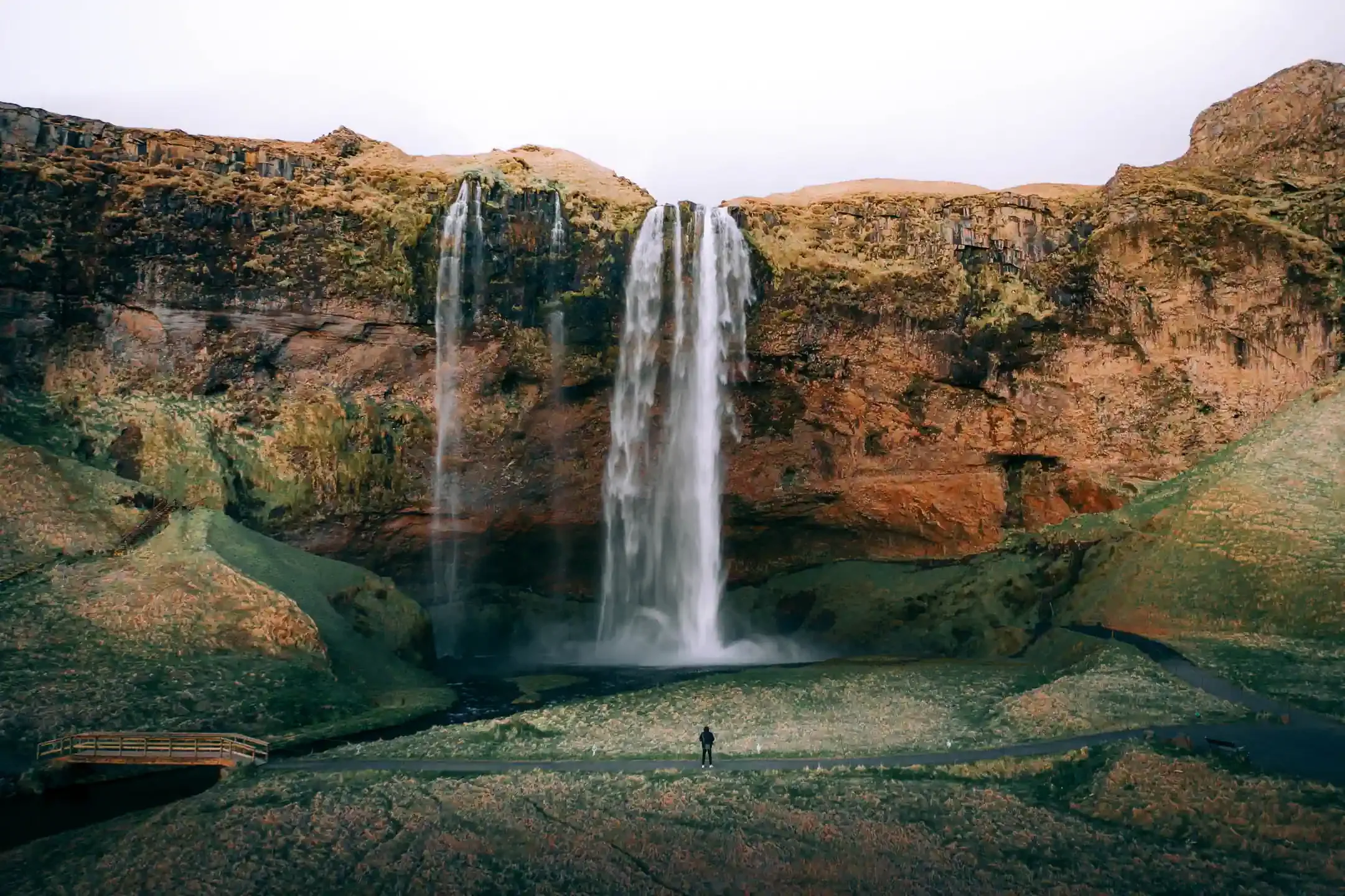 Seljalandsfoss waterfall in South Iceland during summer Iceland road trip with traveler standing near the falls
