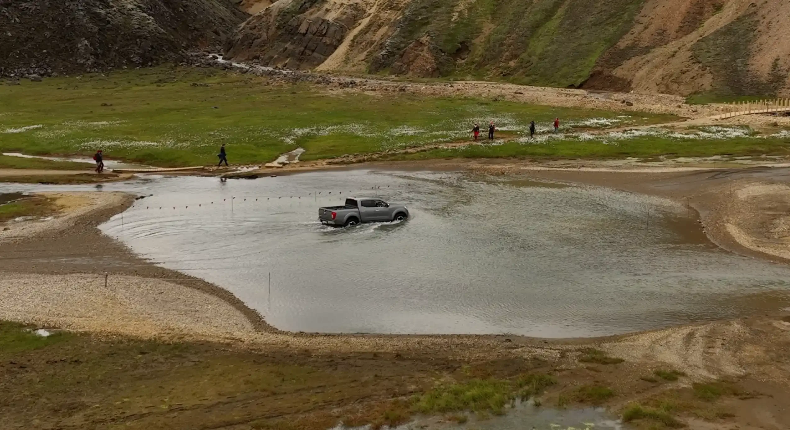 A 4x4 Toyota Hilux crossing an Iceland river at a steady, controlled pace